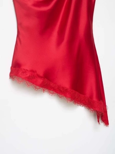 Detailed view of red satin hem with asymmetric cut and matching delicate lace trim