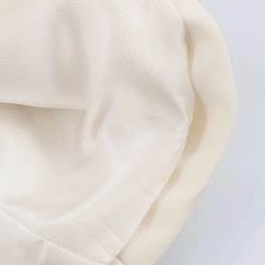 Gros plan détaillé montrant le tissu satiné lisse et la texture douce de la chemise crème