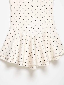 Detail of layered ruffle hem with black polka dot pattern on cream white fabric