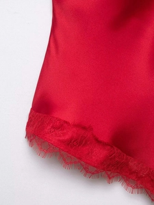 Detail of red satin fabric featuring delicate eyelash lace trim on the hemline