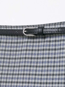 Detail showing blue plaid skirt waist with slim black leather belt and silver metal buckle