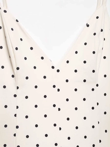 Detail of V-neckline and black polka dot pattern on cream sleeveless summer dress