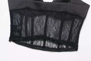 Nahaufnahme von schwarzem Satin-Korsett-Top mit floraler Spitze und integrierten Stäben