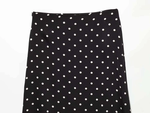 Detailed close-up showing the smooth side zipper and white polka dots on the black skirt