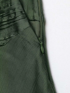 Close-up of deep green satin fabric with textured pleats and a concealed zipper closure