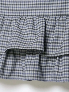 Close-up of blue and white plaid fabric with layered ruffle and pleated design detail