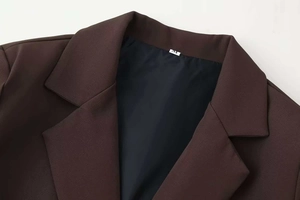 Close-up of deep V-neck collar on a slim brown blazer with woven texture and size M label