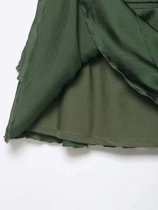 Detail of forest green satin mini skirt showing pleated texture and smooth inner lining
