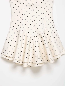 Detail of white polka dot dress featuring a hidden back zipper and ruffled hemline