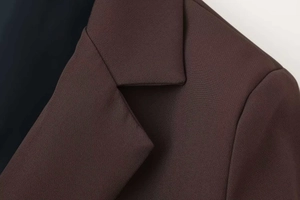 Macro shot of notch lapel detail on deep brown slim fit blazer with fine twill texture