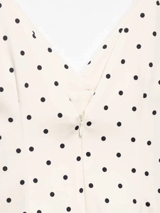 Detail of V-neckline with invisible zipper on cream polka dot sleeveless dress