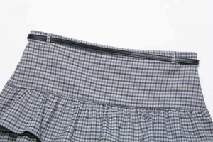 Detail of grey plaid skirt featuring high-waisted design with matching black slim belt