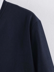 Close-up of navy blue jacket featuring white ribbed collar and twill fabric texture
