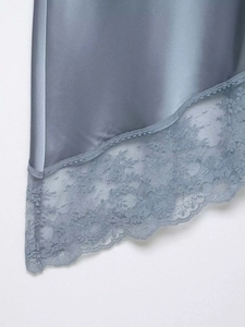 Detailed view of the dusty blue satin hem featuring elegant floral eyelash lace trim