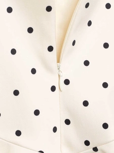 Detailed close-up of invisible zipper and black polka dot fabric on white summer dress