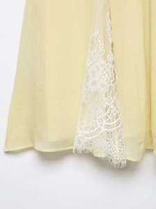 Detailed close-up of white floral lace trim on the hem of a yellow summer mini dress