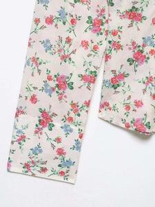 Detail of floral print fabric featuring red roses and blue flowers on off-white woven material