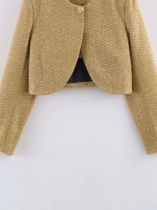 Detailed close-up of gold tweed jacket fabric texture with subtle shimmering sequins