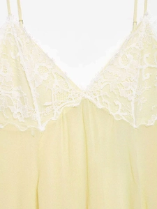Detail of yellow V-neck summer dress with white floral lace trim and spaghetti straps