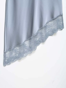 Detail of light blue satin skirt with delicate lace trim and asymmetric hem design