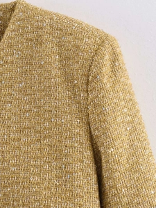 Detail of gold tweed jacket fabric with shimmering silver sequins and texture