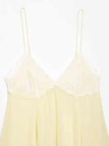 Close-up of light yellow dress featuring white lace trim and thin spaghetti straps