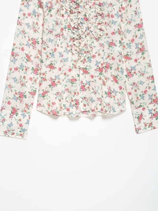 Detail of ruffled trim on floral long sleeve shirt with vintage print on cream fabric