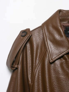 Detail of the brown faux leather collar, epaulette with black button and inner lining
