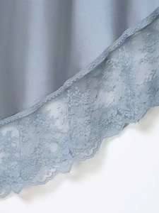 Detail of grey-blue satin skirt hem featuring delicate floral lace trim and smooth texture
