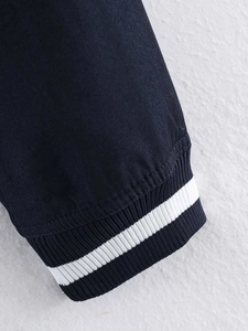 Detail of navy blue jacket cuff with ribbed texture and double white sporty stripes
