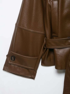 Detail of dark brown faux leather jacket featuring buttoned cuffs and belted waist texture