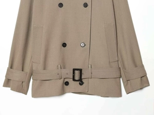 Detail view of double-breasted khaki trench coat with buttons and buckled waist belt