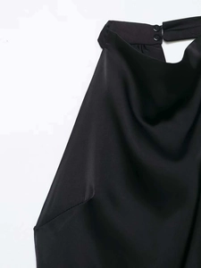 Détail macro d'une robe dos nu en satin noir montrant la fermeture à deux boutons