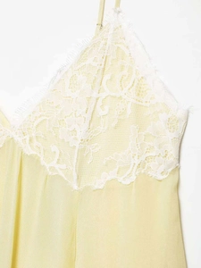 Close-up of pale yellow summer dress with white floral lace trim and eyelash edges
