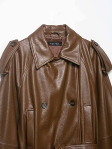 Detail of brown faux leather trench coat showing lapels, shoulder tabs and button texture