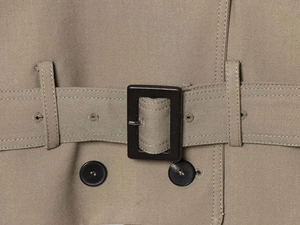 Detailed macro view of khaki twill fabric trench coat with belt and dark resin buckle