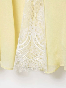 Detail of yellow summer dress with delicate white floral lace hem and eyelash trim