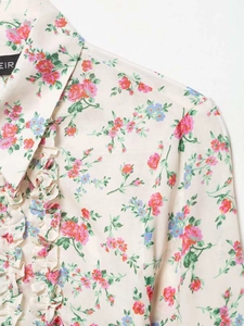 Detail of floral print shirt featuring ruffles and a standing collar on cream fabric