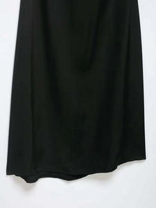 Vue détaillée du satin noir lisse et de la coupe irrégulière de l'ourlet de la robe