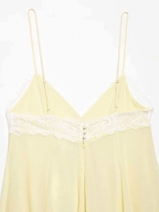 Detailed view of pale yellow mini dress featuring intricate white lace back and silk buttons