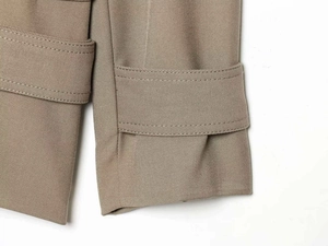 Detailed close-up of khaki trench coat cuff with decorative strap and double stitching