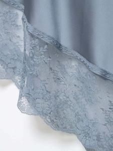 Detail shot of the light blue satin fabric with intricate floral lace trim and embroidery