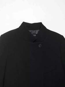 Close-up of Mandarin collar and button detail on black minimalist blazer jacket