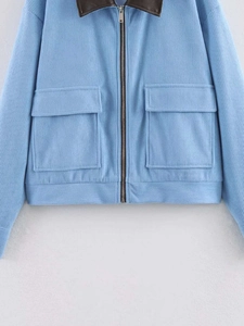 Close-up of light blue corduroy jacket with brown leather collar and metal zipper