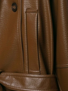 Detail of brown faux leather jacket featuring double stitching and round button pocket
