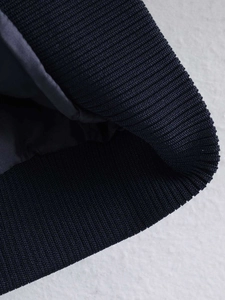 Detail view of navy blue jacket featuring ribbed knit cuffs and smooth fabric texture