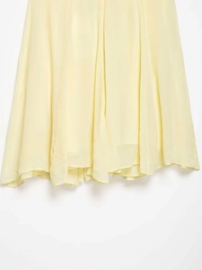 Close-up of light yellow lace dress hem featuring airy chiffon fabric and fine stitching
