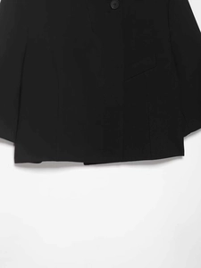 Close-up of black blazer featuring detailed stitching, round button and pocket flap