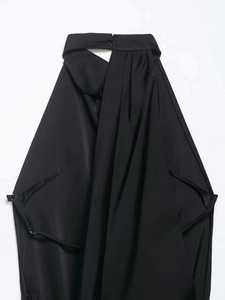 Détail d'une élégante robe dos nu noire avec texture plissée et finition satinée