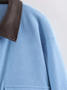 Detail of light blue ribbed knit fabric with contrasting brown faux leather collar design